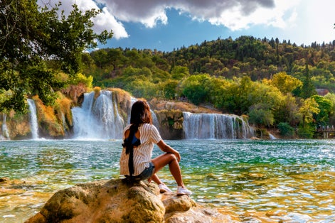 Photo of woman relaxing in the park of the krka national park Croatia on a bright summer evening.