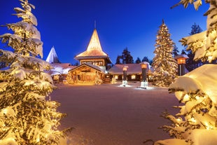 Photo of stunning sunset view over wooden huts and snow covered trees in Kuusamo, Finnish Lapland.