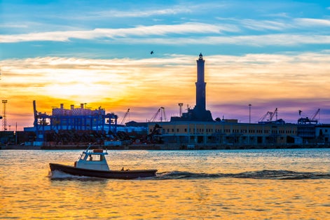 photo of sunset at Genoa's port, silhouette of the Lanterna: the main lighthouse and symbol of the city, in Italy.