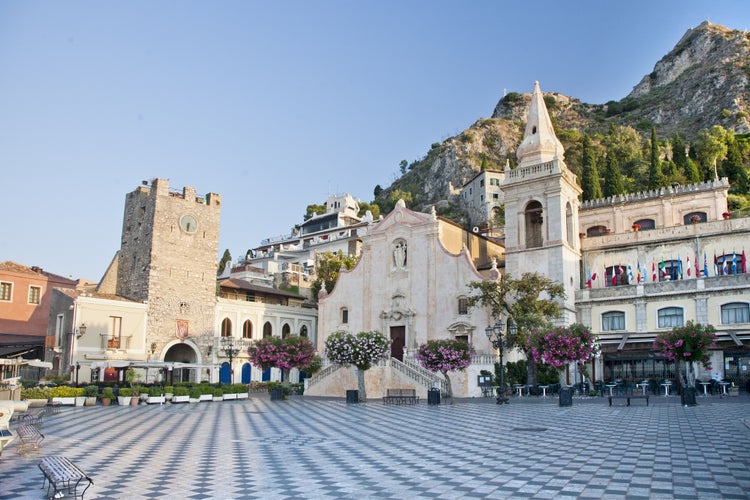 Photo of morning panoramic view of Taormina main square (Piazza IX Aprile) with San Giuseppe Church, the Clock Tower and Mount Etna Volcano on background ,Taormina, Sicily, Italy.