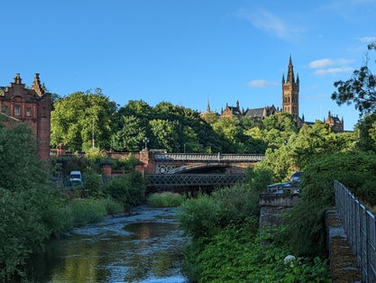 photo of view of View of Glasgow University, Glasgow, Scotland. In the image you can see the bridge over the river, the greenery of the trees and the beautiful tower of the university.