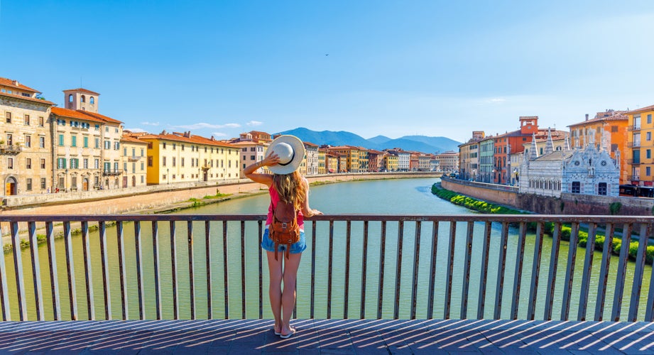 Tourist female in Pisa, Arno river, lamp and buildings reflection. Lungarno view.santa maria della spina