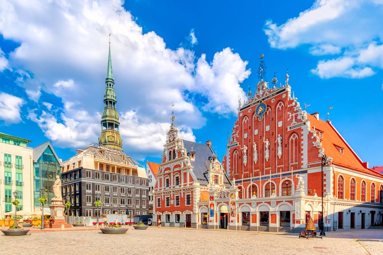 Photo of the Old Town Ratslaukums square, Roland Statue, The Blackheads House and St Peters Cathedral against blue sky in Riga, Latvia. 