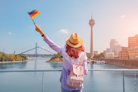 photo of view of A young happy Asian girl with a German flag poses at the Media Harbor and TV-tower in Dusseldorf. Studying language abroad and traveling concept