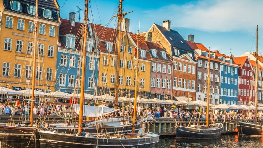 Nyhavn harbor in Copenhagen with colorful buildings, wooden ships, and lively outdoor cafes on a sunny day..jpg