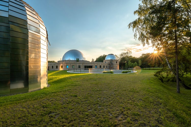 photo of Sunset at the Silesian Planetarium. Reflecting the sky and sunbeams of the planetarium and observatory domes. Aluminum panels on the roof. Chorzow, Silesian Park, Poland.