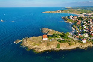 Photo of Saint Anastasia Island in Burgas bay, Black Sea, Bulgaria. Lighthouse tower and old wooden buildings on rocky coast.