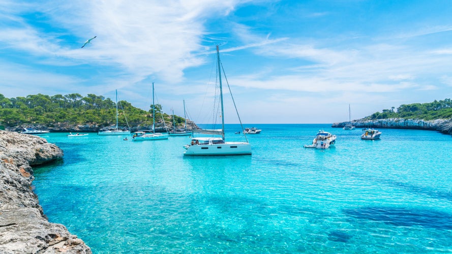 Photo of landscape with boats and beautiful turquoise sea water on Cala Mondrago, Majorca island, Spain.