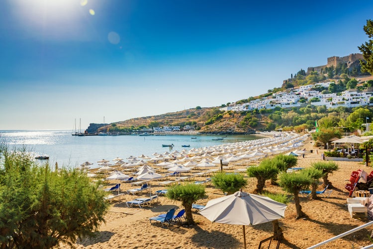 Photo of view of sandy beach in Bay of Lindos, Acropolis in background ,Rhodes, Greece.