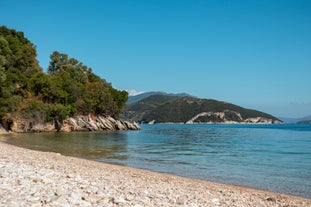 Photo of aerial view of black Perissa beach with beautiful turquoise water, sea waves and straw umbrellas, Greece.