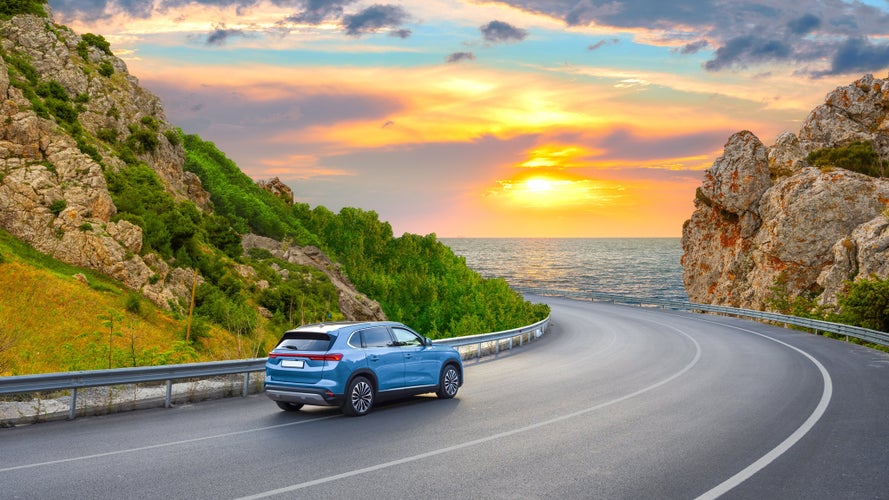 car driving on beautiful road in colorful sunset landscape in summer.jpg