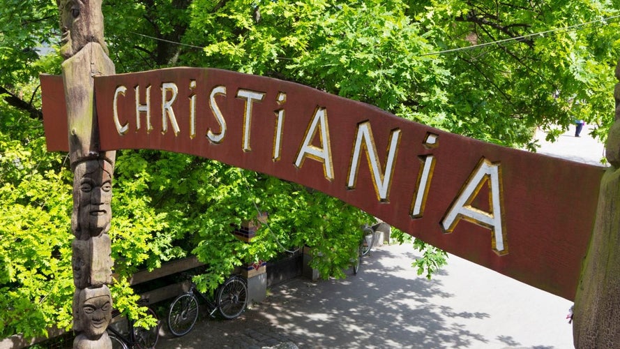 The entrance sign to Christiania, Copenhagen-s famous free town, surrounded by lush green trees and unique carvings..jpg