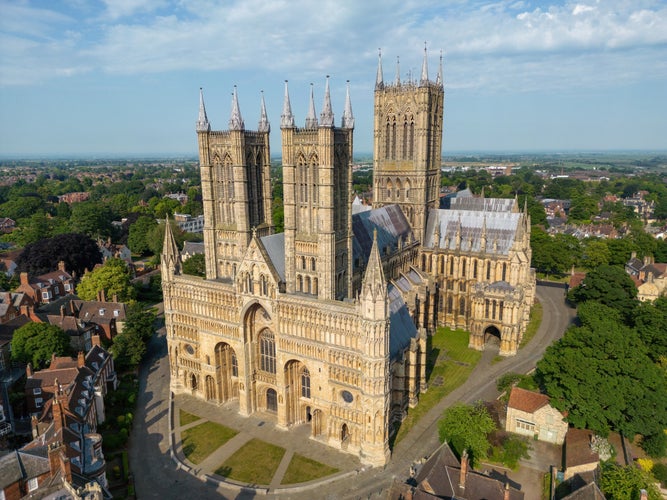 Photo of Lincoln cathedral in beautiful evening golden light with view of unique perspective stunning west face yellow stone on top of steep hill majestic gothic architecture, England.