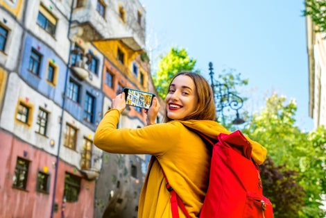 photo of view of Young female tourist photographing with smart phone Hunderwasser building in Vienna, Austria.