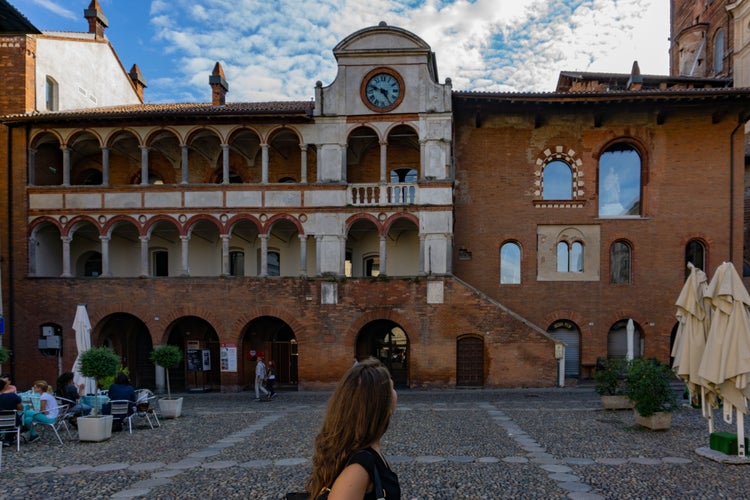 Girl looks at Palazzo Broletto in Piazza della vittoria in Pavia, Lombardy, Italy