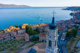 Photo of Old harbour Porto Vecchio with motor boats on turquoise water, green trees and traditional buildings in historical centre of Desenzano del Garda town, Northern Italy.