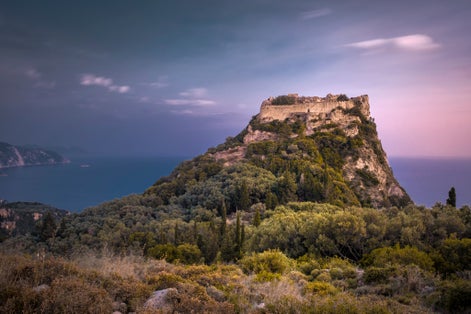 photo of view of Fortress Angelokastro on mountain at sunset. Corfu, Greece..