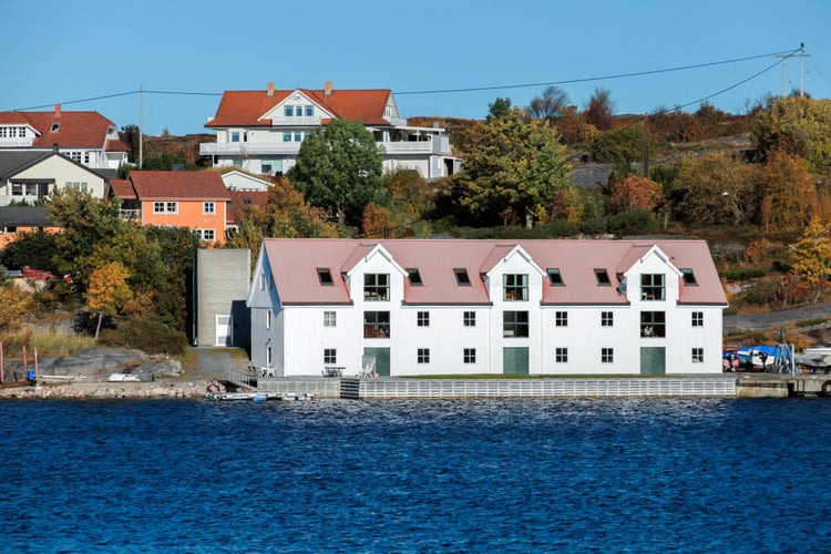 photo of view of Coastal Norwegian town landscape view with white wooden barn and houses on a background. Kristiansund, Norway.