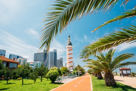 Photo of old Tower And Modern Skyscraper Residential House On Blue Sky Background In Batumi.