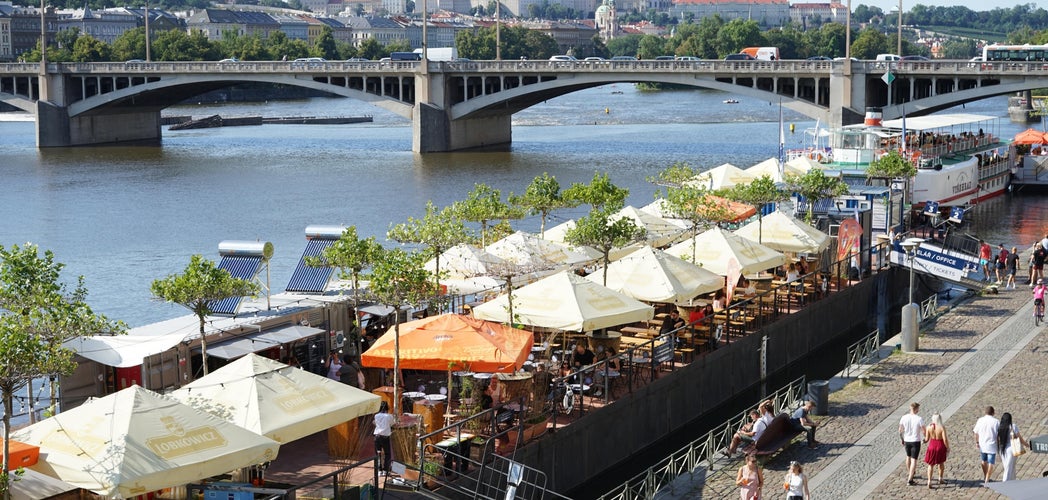 Summer riverside dining along the Vltava River in Prague, with Prague Castle in view during Czechia in July..jpg
