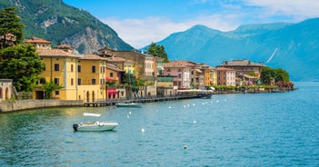 Photo of Old harbour Porto Vecchio with motor boats on turquoise water, green trees and traditional buildings in historical centre of Desenzano del Garda town, Northern Italy.