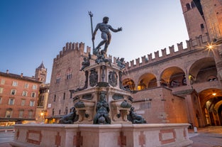 Photo of Italy Piazza Maggiore in Bologna old town tower of town hall with big clock and blue sky on background, antique buildings terracotta galleries.