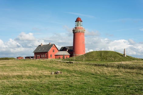 Photo of beautiful red Lighthouse Bovbjerg Fyr with green grass and blue sky, Danish North Sea coast, Jutland, Denmark.