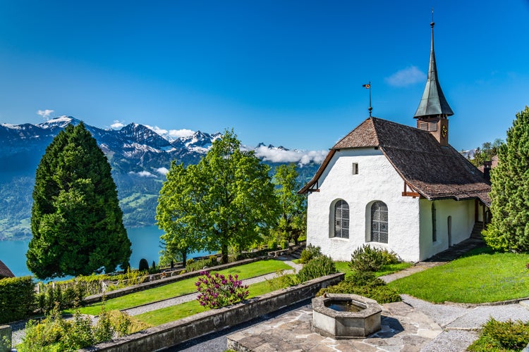 Photo of Christian place of worship and religion. Evangelical Reformed parish of Beatenberg, Switzerland under the cloudy sky in Swiss Alps and Thun lake (Thunersee) on background.