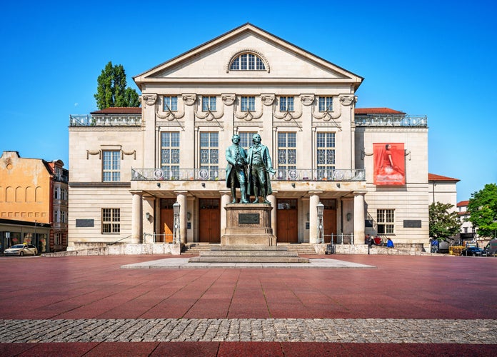 Scenic panoramic view of famous Deutsches Nationaltheater with iconic Goethe-Schiller monument in the old historical city center of Weimar on a beautiful sunny day with blue sky, Thuringia, Germany