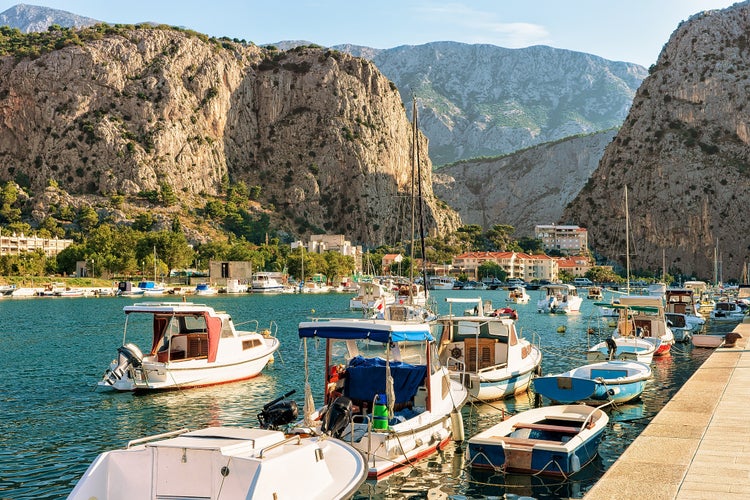 Photo of fishing and sailing boats on the Cetina river in Omis resort. Anchored boats and high mountains in background, Omis, Makarska riviera, Dalmatia, Croatia.