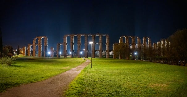 Photo of The Acueducto de los Milagros a Roman aqueduct in Mérida, Extremadura Spain at night .