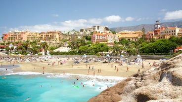 photo of aerial shot of Costa Adeje area, South Tenerife, Spain. Captured at golden hour, warm and vivid sunset colors. Luxury hotels, villas and restaurants behind the beach.