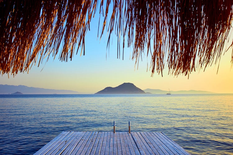 Photo of Bungalow on the sea at sunset. Wooden pavilions on the shore of a sandy beach, Bodrum, Turkey