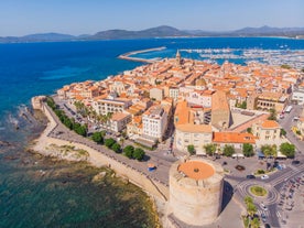 Photo of aerial view of Alghero on a beautiful day with harbor and open sea, Italy.