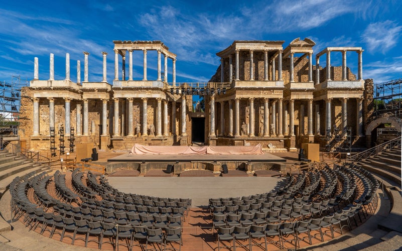 photo of view of Mérida Roman theater from behind with a view of the chairs, granite steps and the stage scaenae frons of classical Roman columns and statues for the Merida International Classical Theater Festival.