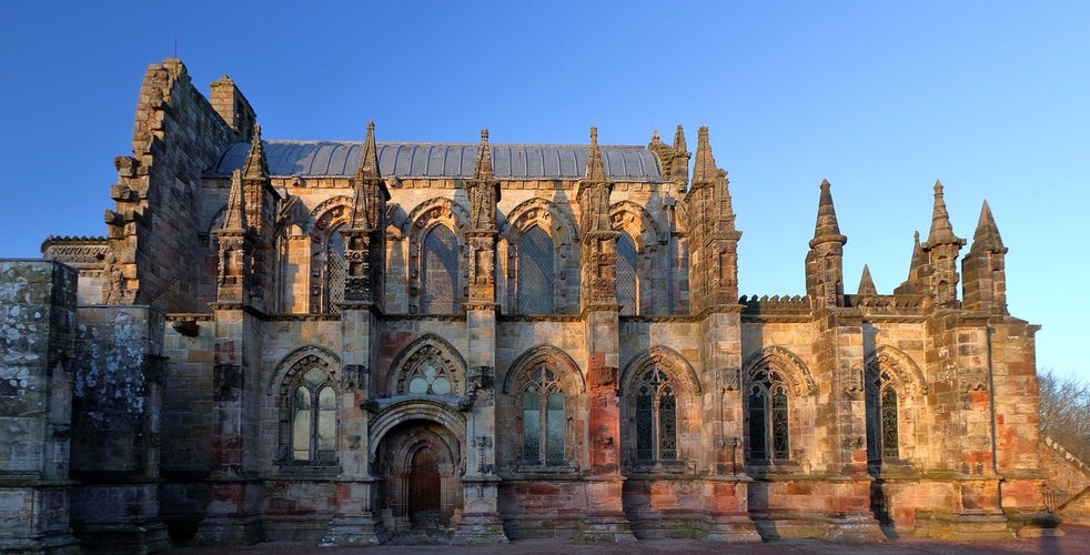 Rosslyn Chapel, a stunning example of intricate Gothic architecture, standing majestically under a clear sky in Midlothian, Scotland.jpg