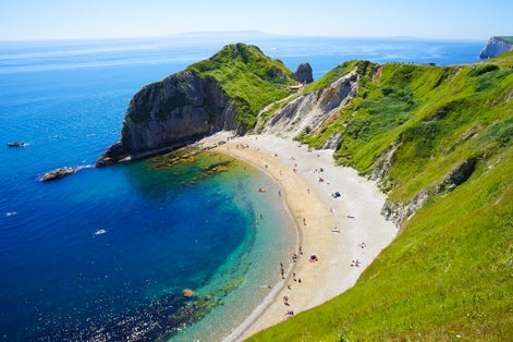 Photo of people enjoying the lovely sunny morning at Lulworth Cove on Dorset's Jurassic Coast in south-west England.