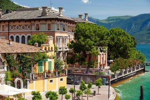 Photo of Old harbour Porto Vecchio with motor boats on turquoise water, green trees and traditional buildings in historical centre of Desenzano del Garda town, Northern Italy.