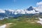 photo of clouds covering snowy mountains and Swiss Alps landscape with meadow and green nature at Männlichen, Grindelwald mountains, Bernese Alps, Switzerland.