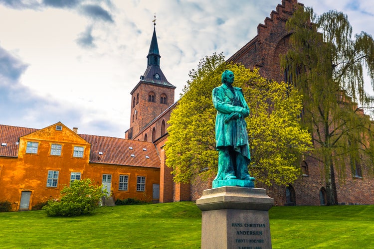 Photo of Monument from 1888 for the Danish author Hans Christian Andersen, Odense cathedral in background, Denmark.