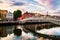 Photo of view of famous illuminated Ha Penny Bridge in Dublin, Ireland at sunset.