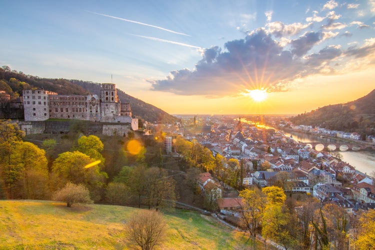 photo of view of View over an old town with a castle or palace rune in the evening at sunset. This place is located in a river valley of the Neckar, surrounded by hills. Heidelberg, Baden-Württemberg, Germany