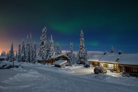 Photo of stunning sunset view over wooden huts and snow covered trees in Kuusamo, Finnish Lapland.