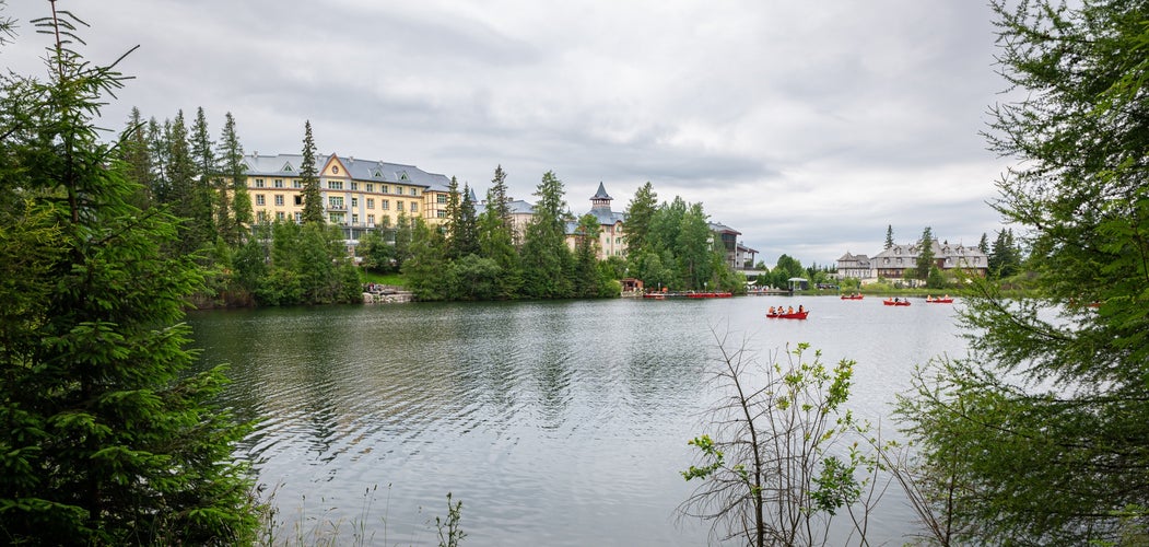 photo of scenic view of buildings along a lake in tourist resort Štrbské Pleso in Tatra Mountains of Slovakia.