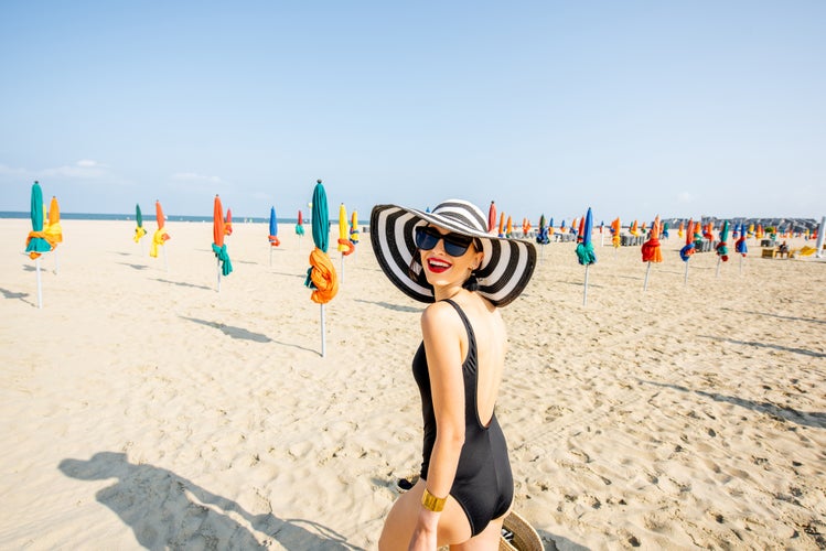 Photo of Woman walking on the beach with colorful umbrellas in Deauville, famous french resort in Normandy