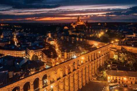 photo of view of Segovia Cathedral and aqueduct aerial view at night in Spain.
