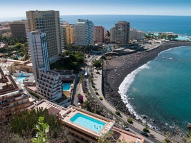 Photo of aerial view with Puerto de la Cruz, in background Teide volcano, Tenerife island, Spain.