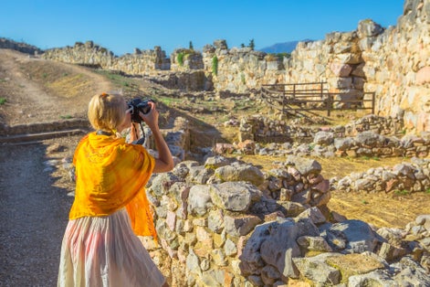 Photo of traveler woman photographer takes shot of Archaeological Site of Ancient Mycenae, Peloponnese, Greece. 