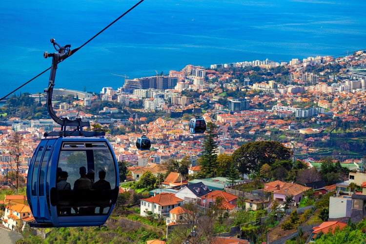 Photo of erial view of Funchal with traditional cable car above the city.