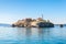 Photo of Saint Anastasia Island in Burgas bay, Black Sea, Bulgaria. Lighthouse tower and old wooden buildings on rocky coast.